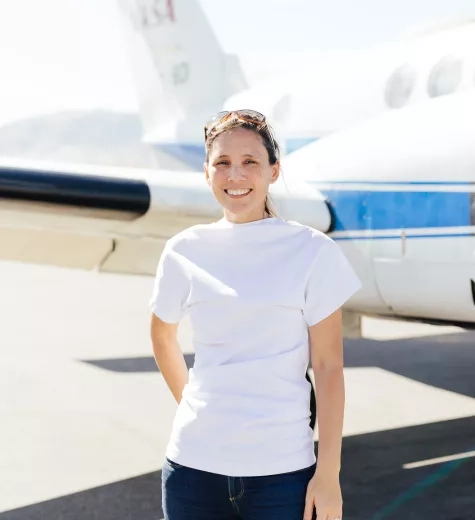 Photo of Melissa in white T-shirt in front of a small NASA branded plane