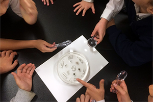 Picture of students examining the contents of a meteorite sample disk. Credit: NASA.