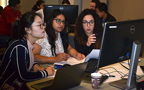 Three students looking at computer monitor