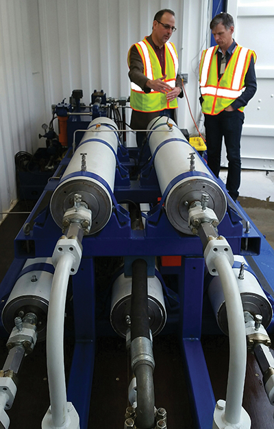 Two men with reflective safety vests standing near SureShear chambers