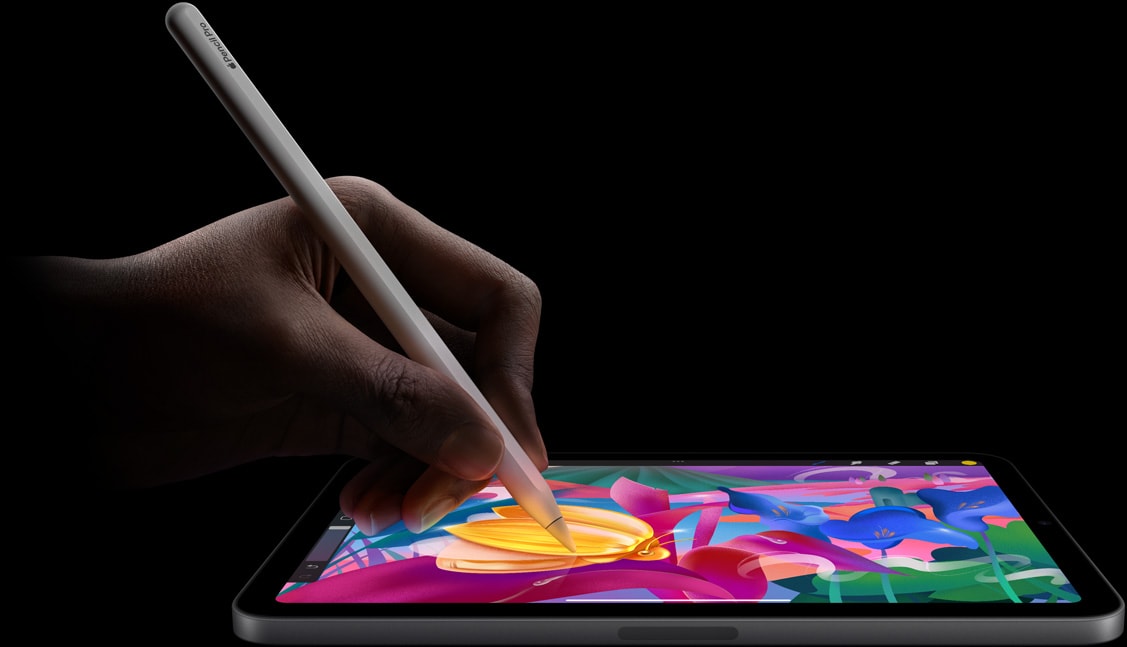 Apple Pencil Pro trzymany w dłoni tworzącej na iPadzie mini barwną pracę plastyczną.