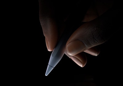 Dłoń z ułożonym do pisania Apple Pencil Pro trzymanym między kciukiem i palcem wskazującym