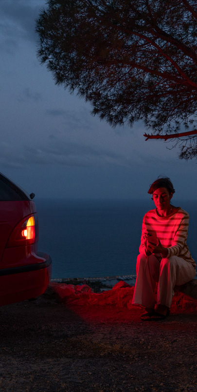 Photo d’une femme assise à côté d’une voiture en panne.