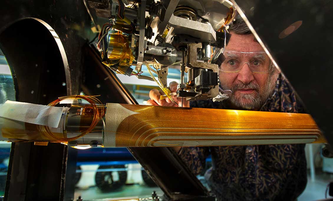 man looking into magnet winding machine