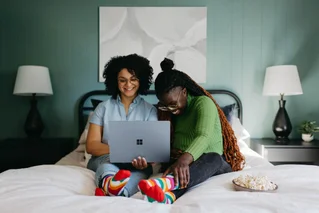 women on bed looking at computer