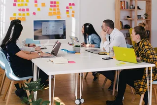 people sitting around a table with computers and post-its