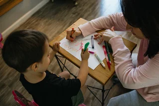 adult coloring on a desk with a child