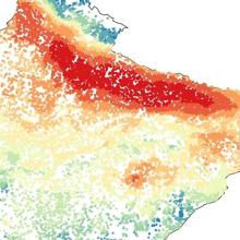 The square image shows dots of different colors representing PM2.5 levels across norther India. Blue and green colors in the lower half of the image indicate lower levels of particulates in the air; yellow and red colors in the upper half indicate areas with high levels of pollutants, such as along the foothills of the Himalayas.