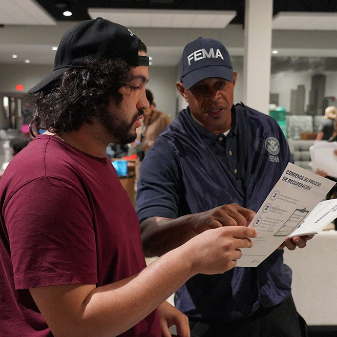 A FEMA employee pointing out information on a flyer to a survivor