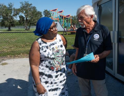 Caption: Tampa, Fla. (Oct. 14, 2024) - A member of FEMA's Disaster Survivor Assistance crew talks with a Hurricane Milton survivor at a Hillsborough County park. DSA Team Members are out and about in the affected communities, ready to take an application or answer questions. Photo by Liz Roll/FEMA