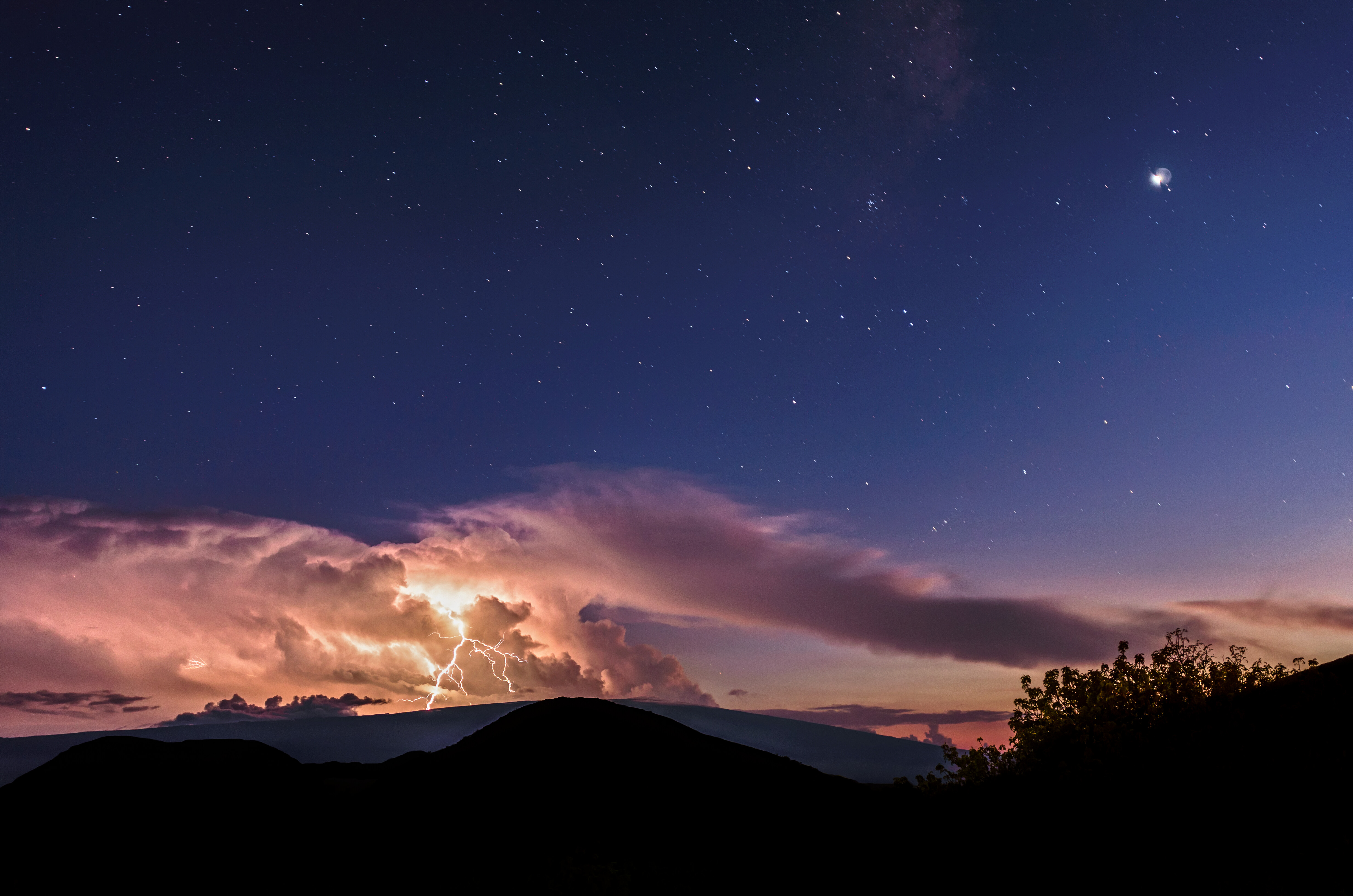 pinkish clouds glow against a dark blue sky