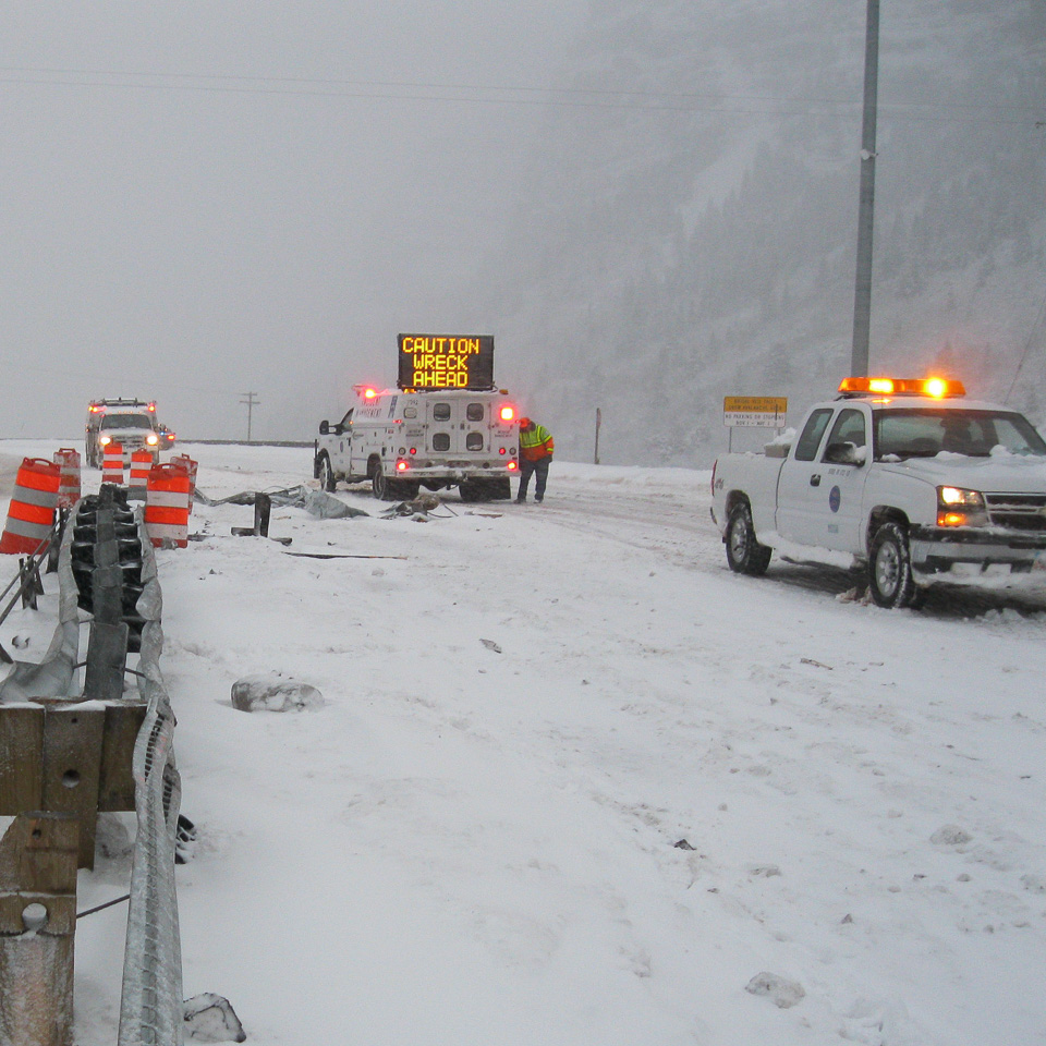 emergency vehicles on a snow-covered highway, sign says 'caution wreck ahead'