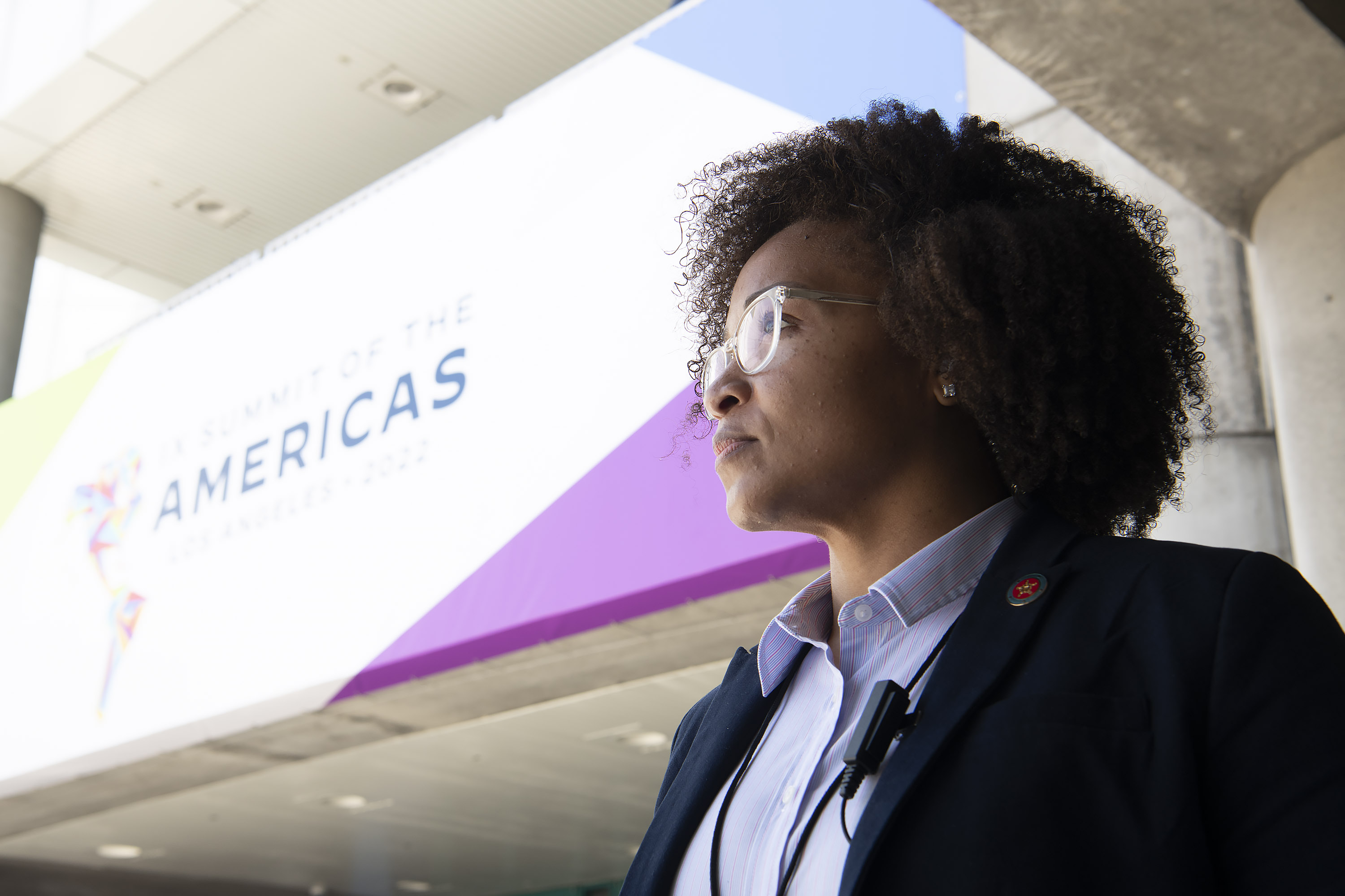 Female special agent with dark, curly hair standing outside of the Summit of Americas. 