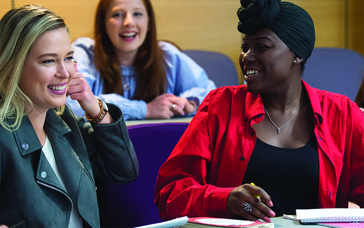 Two students discussing a topic in a lecture theatre at the University of Sussex