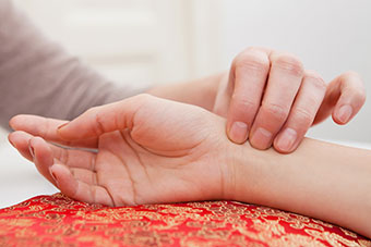 Two hands, one resting on a red cushion