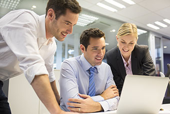 Three people in an office looking at a computer screen