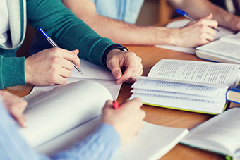 Students around a desk working together with the books open