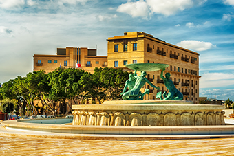 Malta - the Triton Fountain, trees and building in the background