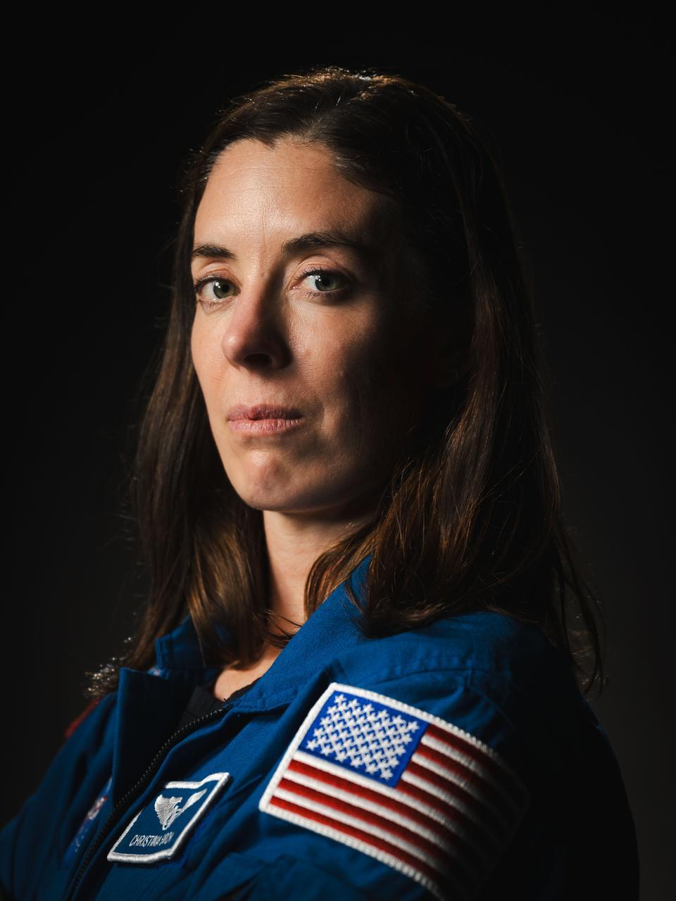 NASA astronaut Chris Birch, a white woman, poses for a portrait at NASA's Johnson Space Center in Houston, Texas. Her body is turned sideways as she looks into the camera. Credit: NASA/Josh Valcarcel