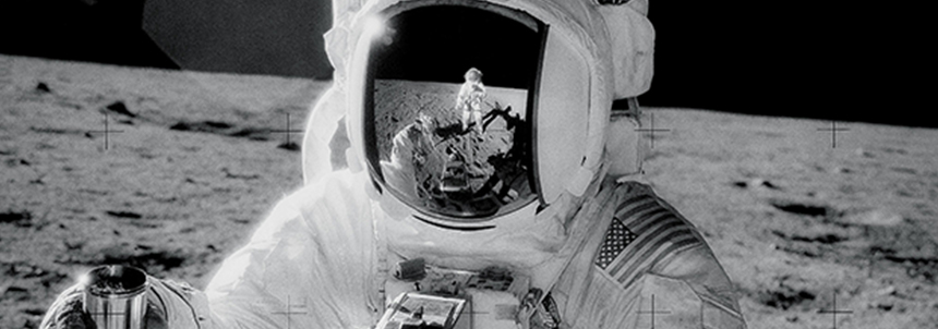 During the Apollo 12 mission, one of the astronauts on the Moon’s surface is holding a container of lunar soil. The other astronaut is seen reflected in his helmet. Credit: NASA