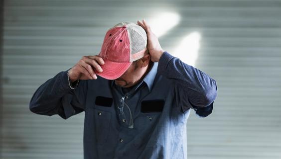 Man putting on a red ball cap hat