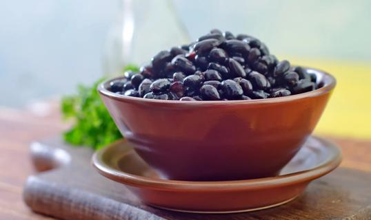 Bowl of cooked black beans on plate on cutting board