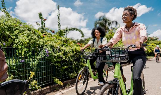 Smiling people riding bicycles on sunny day, blue sky