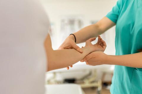 Healthcare provider examining a person's wrist and lower arm