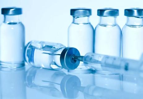 FLu vaccine vials with needle filled with liquid on a blue background.