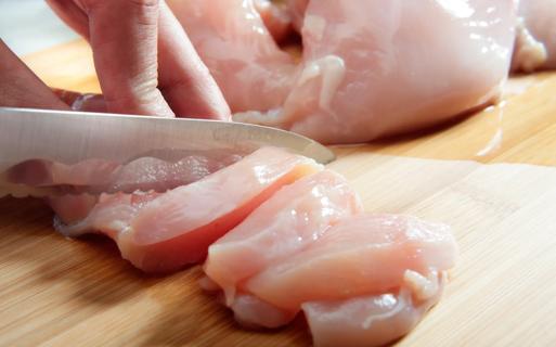 Raw chicken being cut up on cutting board