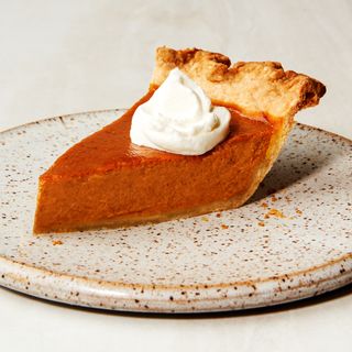 A slice of pumpkin pie with whipped cream on top.