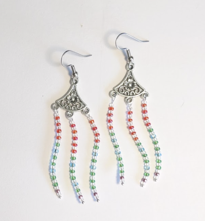 A pair of earrings have red, then green and blue, then a little bit of pink colors, corresponding with aurora