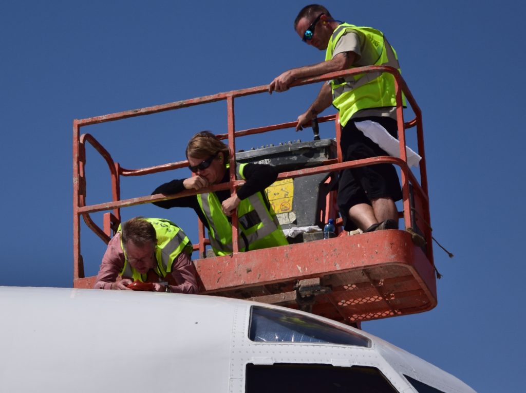 Sebastian Schmidt (center) and his team check the sensor of the Solar Spectral Flux Radiometer that sticks out of the top of the NASA P-3 aircraft. Credit: NASA/Jane Peterson