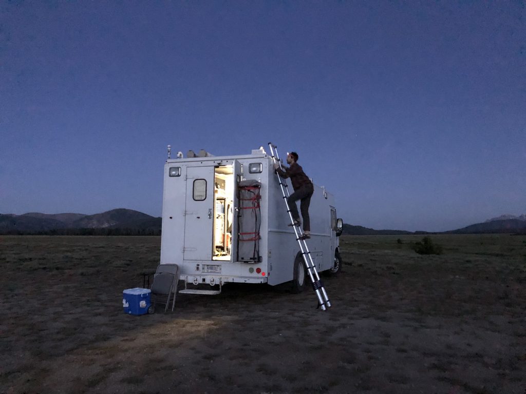 Jackson climbs to the roof of the van to open and set up the inlet valve that will suck exterior air into the van. July 24, 2019. Credit: NASA