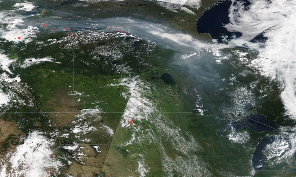 True color satellite image of Canada and the northern United States on July 23, 2019. Fires in northern Alberta (red dots in top left) produced smoke that traveled to the Great Lakes (bottom right) over the course of a few days. Credit: NASA EOSDIS / Worldview 