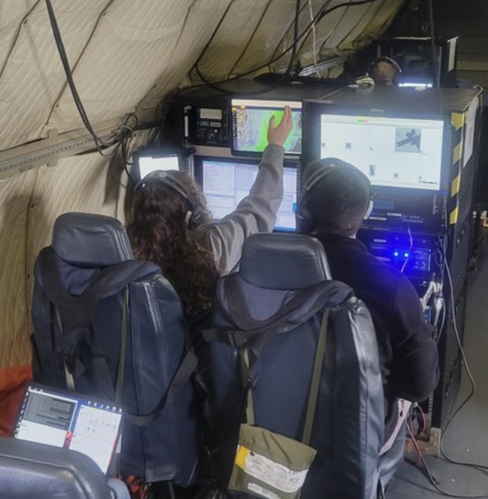 Christian Nairy and Jennifer Moore seated at their in-flight computers in the P3 aircraft.