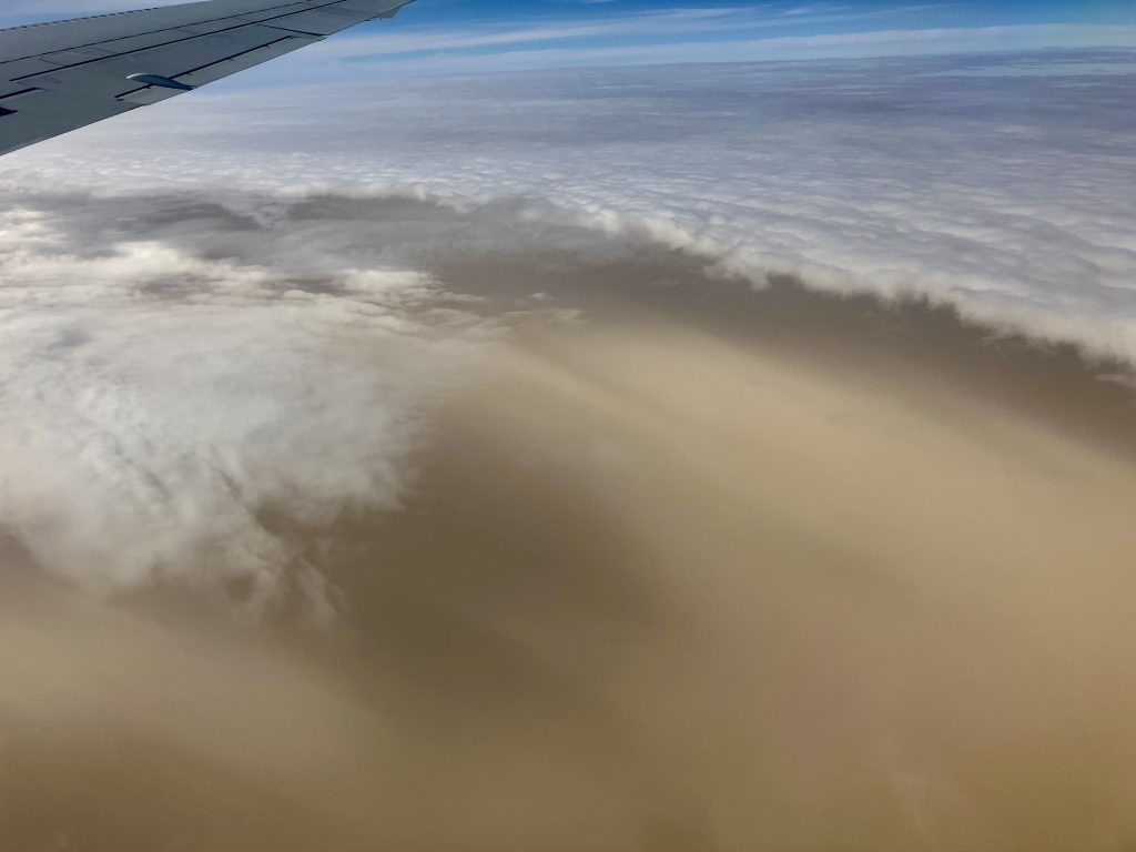 A layer of dust, which appears brown, layered atop a cloud, as seen from the window of the DC-8 aircraft.