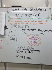 A whiteboard lists the day's schedule.