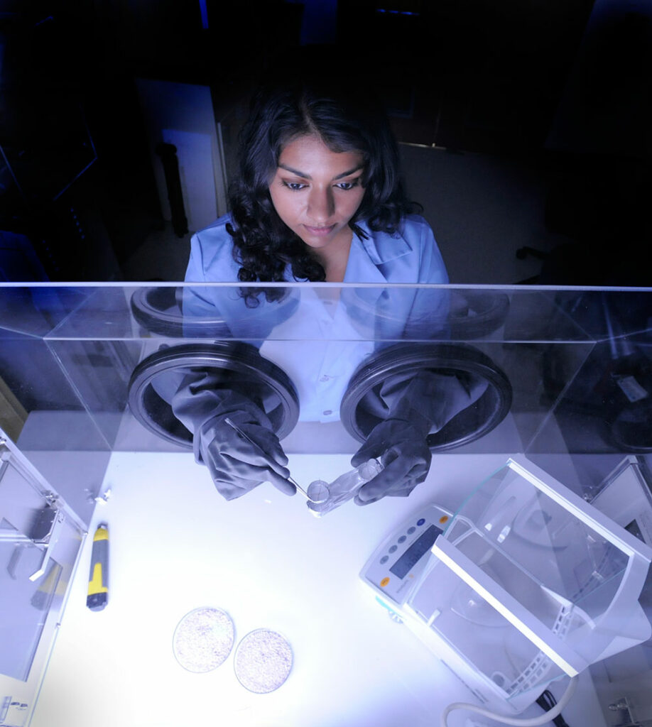 Former NASA intern and current NASA technologist Nithin Abraham uses sterile gloves in a clean container environment study a simple sample in NASA’s Goddard Space Center’s laboratory. Wearing professional attire, she looks in focused while using a small tweezer like tool to interact with small science components. Credit: NASA/Pat Izzo