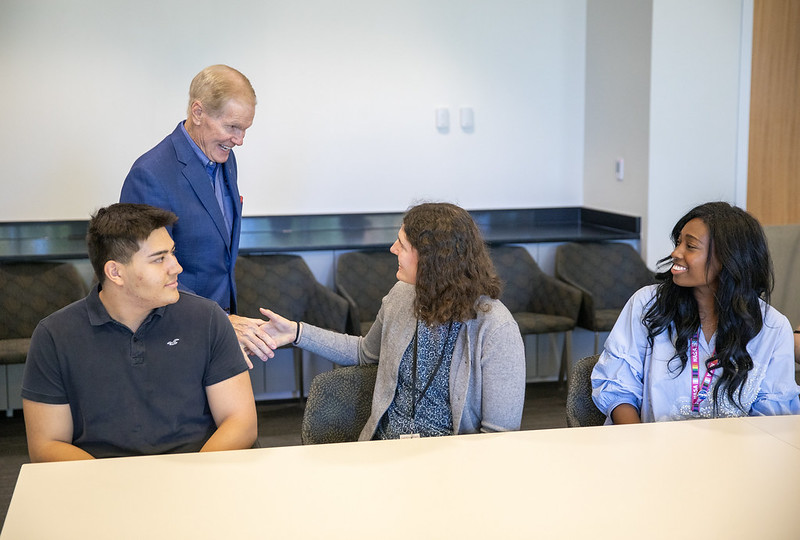 Alt Text: NASA interns including Caitlyn McClanahan meet with NASA Administrator Bill Nelson at NASA's Langley Research Center. Bill Nelson smiles as he shakes an intern hand the other looking on smiling at him. Credit: NASA