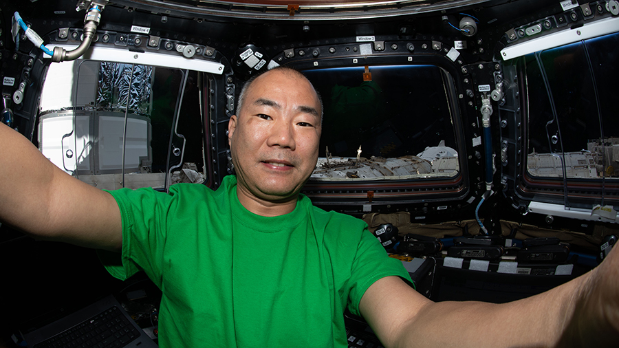 Expedition 64 Flight Engineer Soichi Noguchi of JAXA is pictured inside the cupola with the SpaceX Crew Dragon vehicle visible behind his left shoulder. Credits: NASA