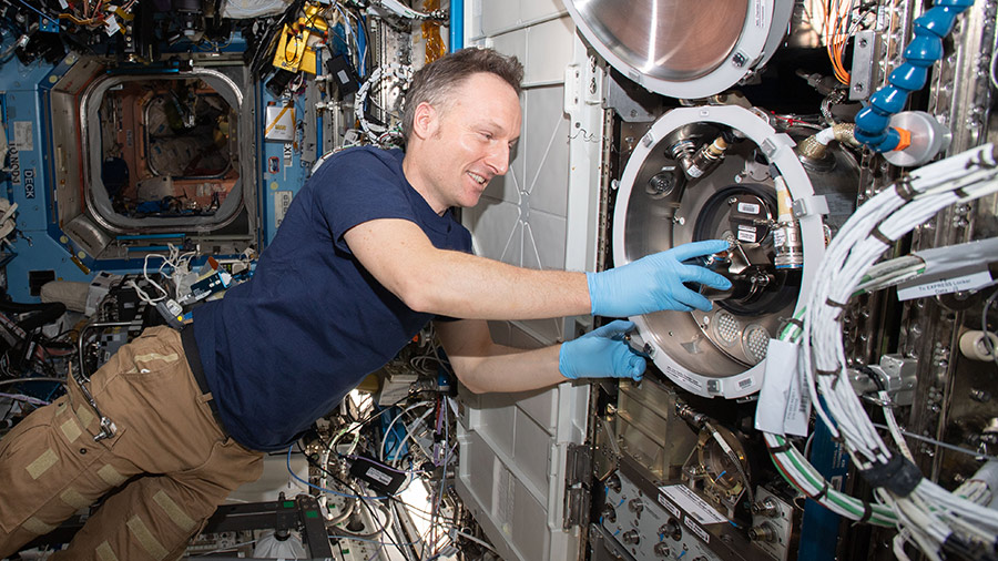 ESA astronaut Matthias Maurer swaps samples inside the Materials Science Laboratory, a physics research device.