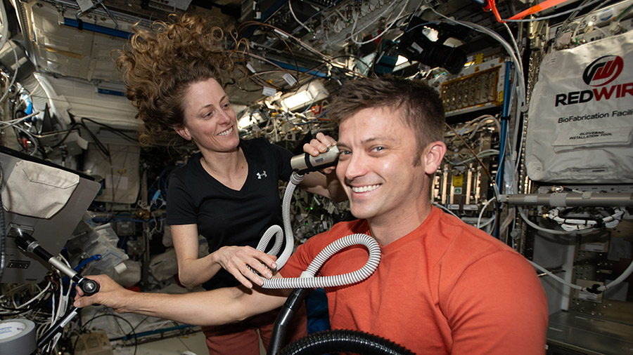 Astronaut Matthew Dominick receives a haircut from astronaut Loral O'Hara.