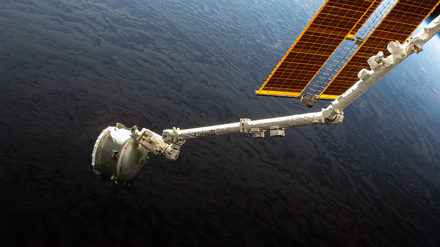 The Nanoracks Bishop Airlock is in the grips of the Canadarm2 robotic arm as it is positioned away from the station prior to jettisoning a trash container for disposal.