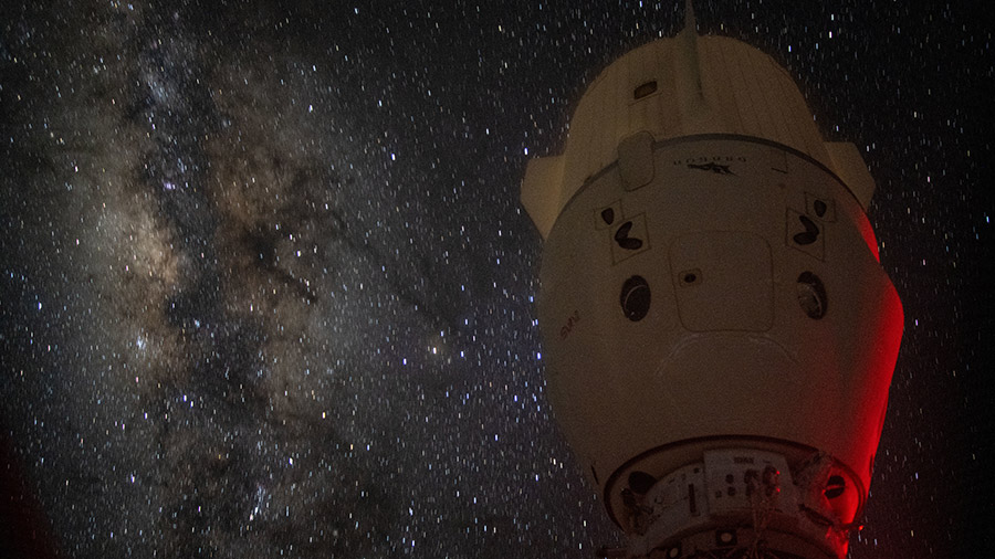 The Milky Way appears in the vastness of space behind the dimly lit SpaceX Dragon Endeavour spacecraft docked to the space station's Harmony module.