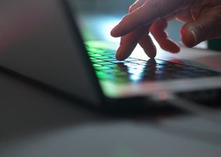 A hand typing on a laptop