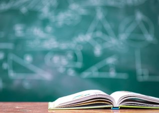 An open book in front of a chalkboard