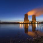 Image of two cooling towers above a body of water.