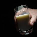 A hand holding a glass of milk.