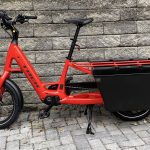 Image of a red bicycle with large plastic tubs flanking its rear wheel.